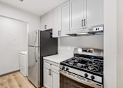 Thumbnail 3 of 31 - A kitchen with a black fridge, stainless steel oven and white cabinets.