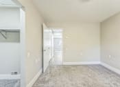 Thumbnail 11 of 30 - A room with a carpeted floor and a doorway leading to another room.