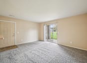 Thumbnail 32 of 39 - A room with a carpeted floor and a sliding glass door leading to a backyard.