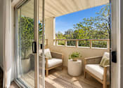 Thumbnail 20 of 35 - A patio with a sliding glass door leading to a balcony with a white couch and a potted plant.