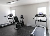 Thumbnail 21 of 25 - A room with a treadmill, a stationary bike, and a rowing machine.