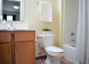 Thumbnail 22 of 38 - A white toilet sits in a bathroom next to a sink and a plant.