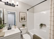Thumbnail 13 of 39 - A white bathroom with a toilet, sink, and a shower.