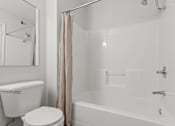 Thumbnail 4 of 39 - A white toilet sits next to a white bathtub in a bathroom.