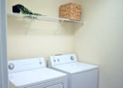 Thumbnail 37 of 38 - Two white front loading washing machines in a laundry room.