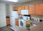 Thumbnail 26 of 38 - A kitchen with a white refrigerator, white oven, and brown cabinets.