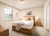 Thumbnail 7 of 22 - Bright bedroom with bed, nightstands, and window at Southwind Apartments in Richland, MS.