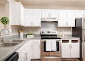 Thumbnail 2 of 22 - Modern kitchen with white cabinets and stainless steel appliances at Southwind Apartments in Richland, MS.