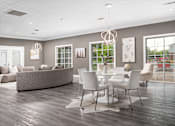 Thumbnail 12 of 22 - Modern community room with grey sofa, white chairs, and wood flooring at Southwind Apartments in Richland, MS.