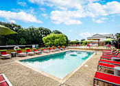 Thumbnail 19 of 22 - Outdoor swimming pool surrounded by red lounge chairs at Southwind Apartments in Richland, MS.