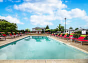 Thumbnail 22 of 22 - Spacious outdoor pool lined with red lounge chairs at Southwind Apartments in Richland, MS.