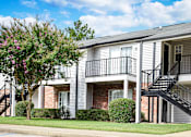 Thumbnail 15 of 22 - Apartment building exterior with grey facade and black metal staircase at Southwind Apartments in Richland, MS.