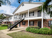 Thumbnail 17 of 22 - Apartment building exterior with white siding and black door and windows at Southwind Apartments in Richland, MS.