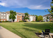 Thumbnail 21 of 38 - A row of apartment buildings with a green lawn in front.