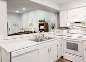 Thumbnail 1 of 37 - A white kitchen with a stove, sink, and cabinets.
