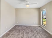 Thumbnail 10 of 26 - A room with a ceiling fan and carpeted floor.