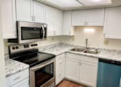 Thumbnail 2 of 16 - A kitchen with white cabinets and a black stove top oven.