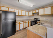 Thumbnail 2 of 21 - Modern apartment kitchen featuring black refrigerator and black stove top oven at Cambury Hills Apartments in Omaha, Nebraska