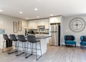 Thumbnail 9 of 16 - A modern kitchen with a bar area and a clock on the wall.