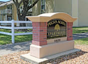 Thumbnail 24 of 26 - a sign for pecan acres apartments in front of a white fence