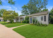 Thumbnail 18 of 26 - a white house with a yard and a sidewalk