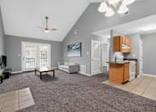 Thumbnail 2 of 18 - A spacious living room with a grey carpet and a ceiling fan.