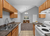 Thumbnail 5 of 18 - A kitchen with a white stove top oven and a white dishwasher.