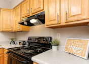 Thumbnail 3 of 21 - A kitchen with wooden cabinets and a black stove top oven.