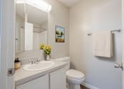 Thumbnail 12 of 32 - A white bathroom with a toilet, sink, and a mirror.