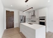 Thumbnail 14 of 29 - A modern kitchen with a white island and stainless steel appliances.