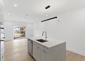 Thumbnail 12 of 29 - A modern kitchen with a sink and a window.