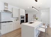 Thumbnail 6 of 29 - A modern kitchen with a white island and stainless steel appliances.