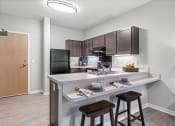 Thumbnail 7 of 19 - a kitchen with a breakfast bar and stools next to a kitchen counter with a
