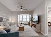 Thumbnail 1 of 26 - A living room with a white couch, a wooden coffee table, and a flat screen TV at Sunday Village