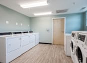 Thumbnail 15 of 26 - a laundry room with washers and dryers and a door to a bathroom at Sunday Village Apartments, Austin, 78723