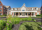 Thumbnail 1 of 35 - A building with a brick facade and a tower on top is surrounded by a garden.