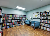 Thumbnail 21 of 35 - A room full of books with a blue chair and a lamp.