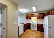 Thumbnail 2 of 35 - A kitchen with white appliances and wooden cabinets.