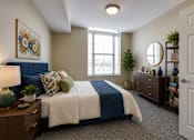 Thumbnail 4 of 35 - A bedroom with a bed, nightstand, and a window.