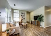 Thumbnail 9 of 35 - A living room with a white couch and wooden floors.