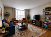 Thumbnail 3 of 35 - A living room with a blue couch, a coffee table, and a television.