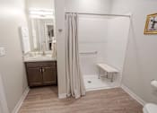 Thumbnail 4 of 20 - A bathroom with a white toilet, a sink with a mirror and a brown cabinet.