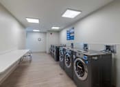 Thumbnail 17 of 19 - A laundromat with a row of washers and dryers.