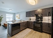 Thumbnail 2 of 19 - A modern kitchen with dark brown cabinets and stainless steel appliances.