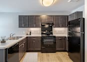 Thumbnail 1 of 19 - A modern kitchen with dark brown cabinets and black appliances.