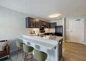 Thumbnail 3 of 19 - A kitchen with a white countertop and green barstools.