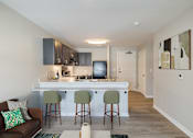 Thumbnail 4 of 19 - A kitchen with a bar and stools.
