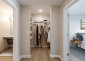Thumbnail 7 of 19 - A hallway with a white door on the left, a bed on the right, and a closet in the middle.