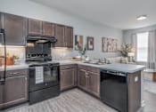 Thumbnail 6 of 20 - A modern kitchen with dark brown cabinets and black appliances.