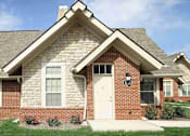 Thumbnail 8 of 35 - A brick house with a white door and windows.